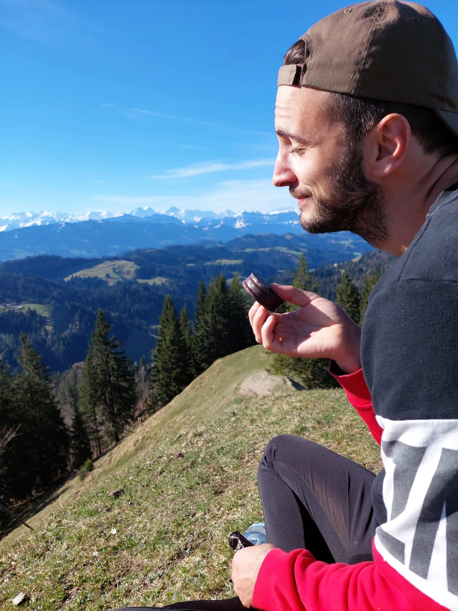 Ein Mann sitzt auf einem Berggipfel und blickt ins Tal