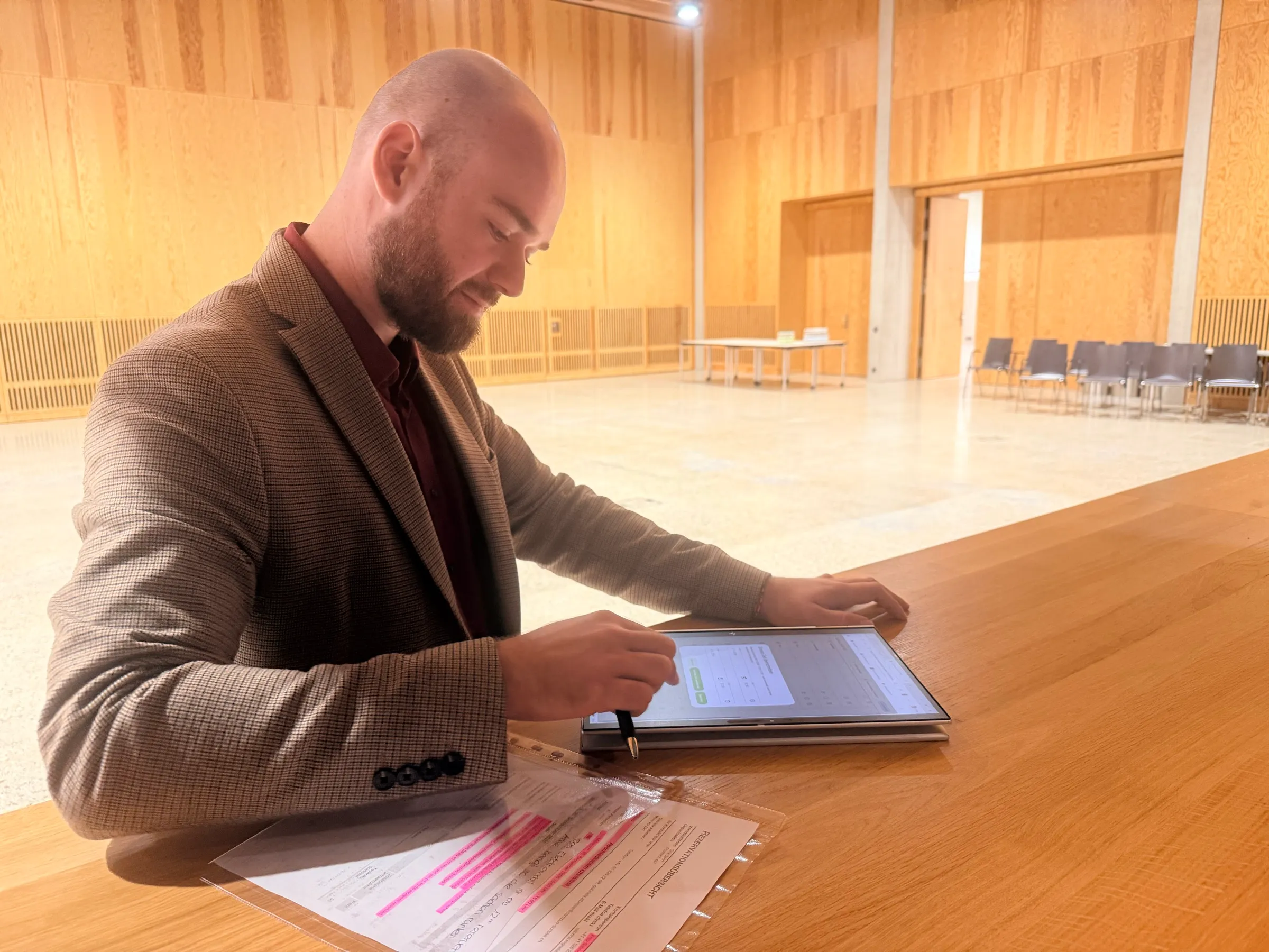 Zsolt Gödri plant an einem Tisch im Eventsaal Einsätze auf dem Tablet, mit dem Stift in der Hand