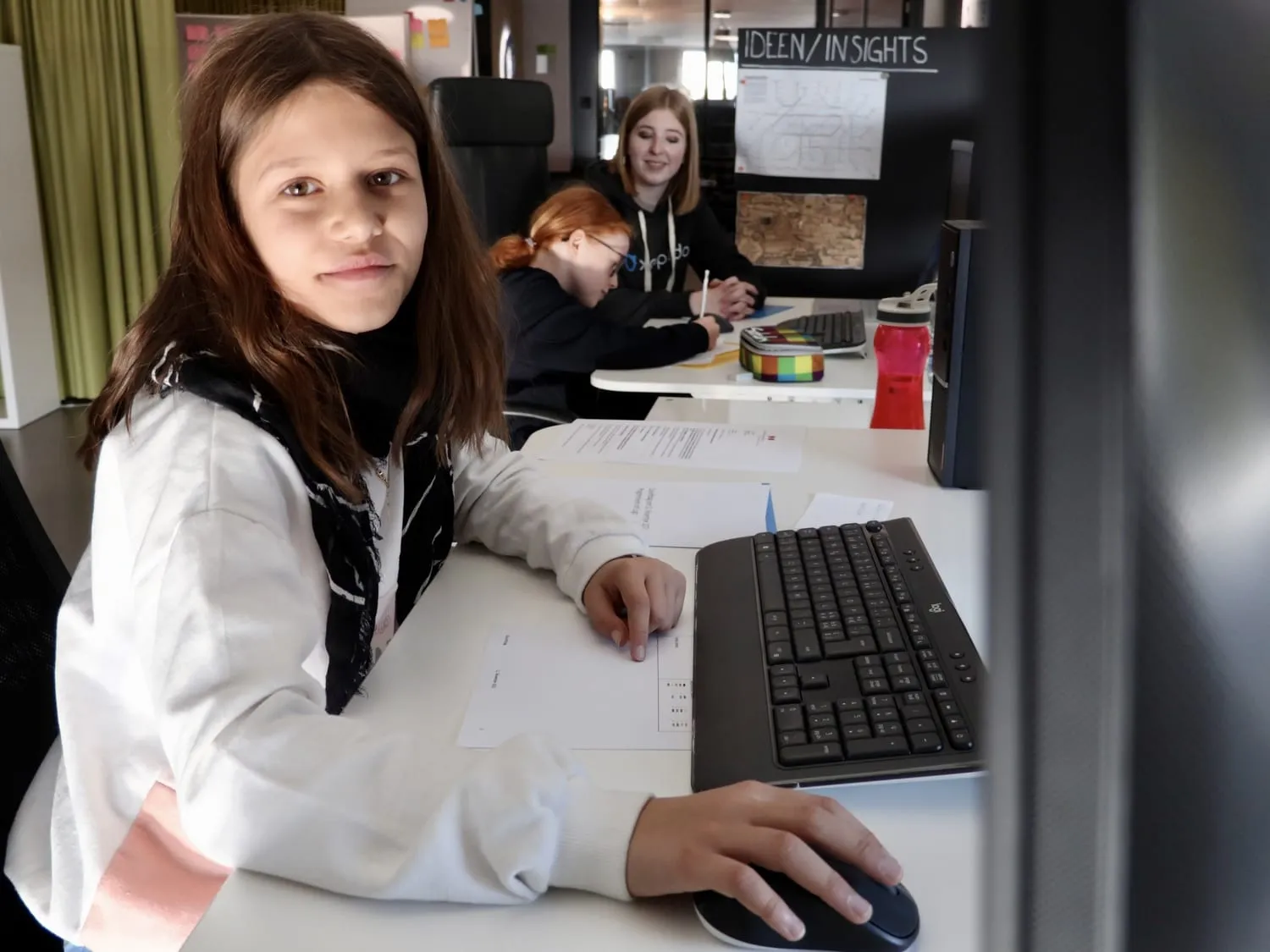 Eine Teilnehmerin am Arbeitsplatz blickt in die Kamera