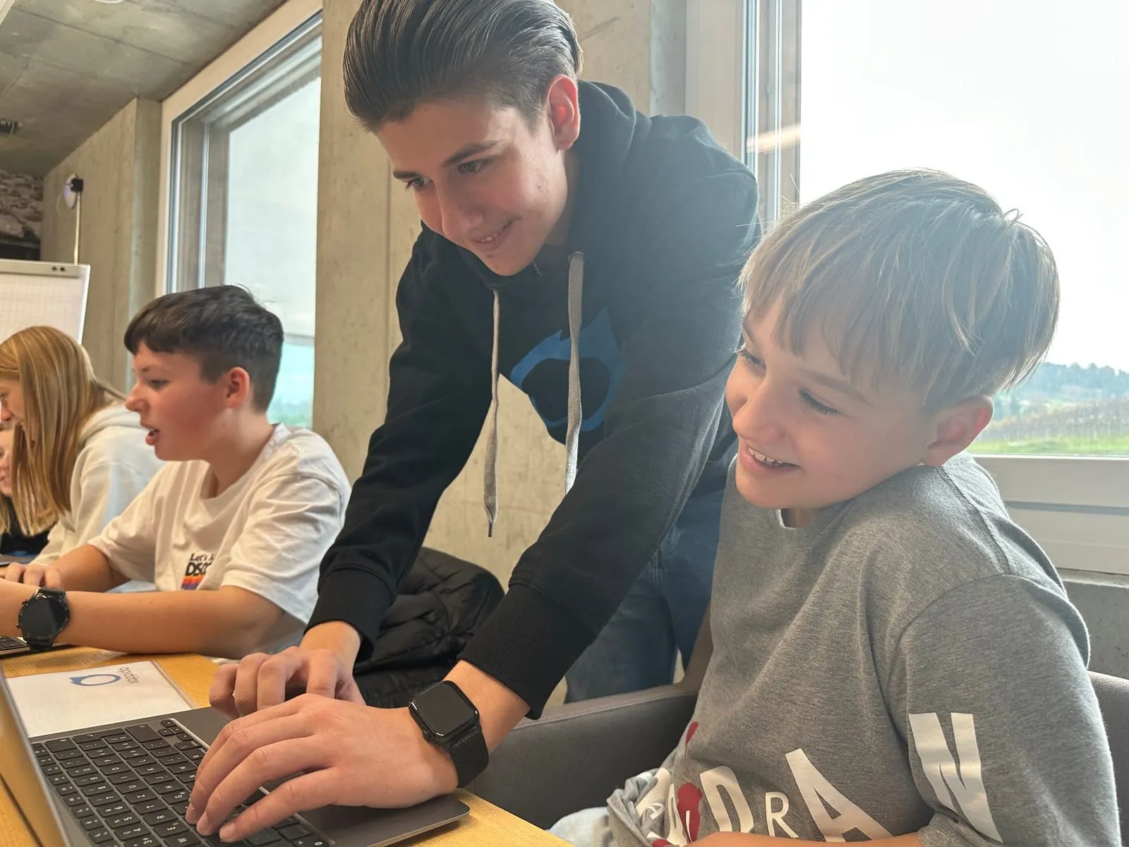 Ein Betreuer hilft einem Schüler am Laptop weiter